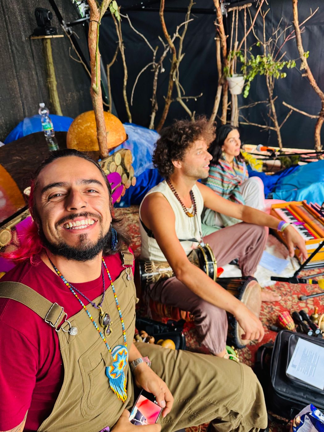 Ro smiling next to musicians with a drum and a harmonium